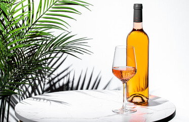 Refreshing rose pink wine served elegantly alongside a bottle and tropical plant in a bright setting