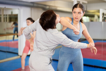Group of women training self-defense techniques in pairs in studio