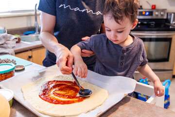 Mother and Toddler Son Making a Homemade Pizza Together in the Kitchen