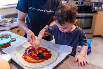 Young Toddler Boy Making Pizza with Parent in a Home Kitchen