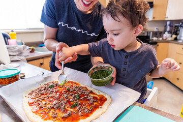 Mother and Young Boy Toddler Making Homemade Pizza Together in the Kitchen
