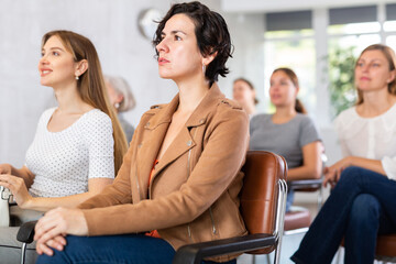 Portrait of focused young Hispanic woman participating study session, sitting in auditorium with...
