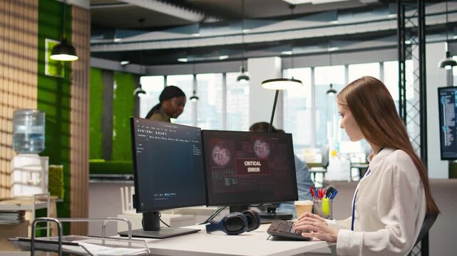 Young inexperienced developer in office struggling to fix critical error warning popup. Intern troubleshooting error notification on computer screen interrupting workflow, camera A