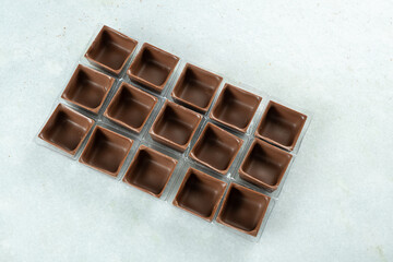 Square-shaped milk chocolate shells inside the molds_top view.