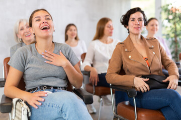 group of female students in lecture hall is sitting and having fun together over joke of tutor....