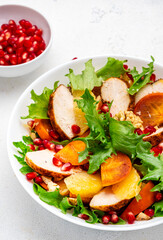 Autumn salad with grilled chicken, persimmon, pomegranate, walnuts, oranges and lettuce, top view