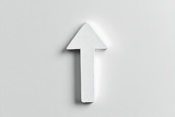 Fototapeta premium A high-angle close-up of a white arrow, likely made of wood, pointing vertically upward against a plain white background