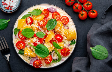 vegan salad with couscous, cherry tomatoes, red onion, fresh baby spinach and juicy orange, top view