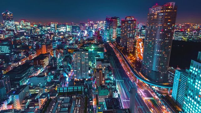 An aerial view captures a vibrant city skyline at night, showcasing shining buildings and busy highways filled with colorful lights. The energy of the metropolis is palpable.