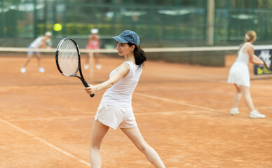 Young woman playing tennis against female opponent on tennis court