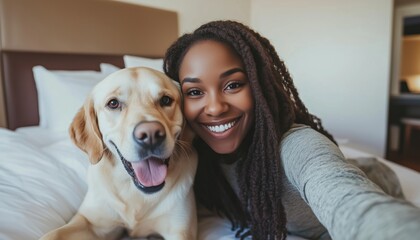 Happy Black Woman Capturing Moment With Dog On Bed In Pet-Friendly Hotel Room.
