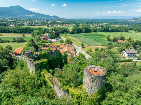 Aerial view of hilltop ruined castle Rochette in Savoy France with round keep, curtain walls rising above the commercial road below