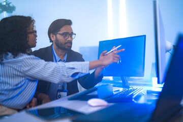 Diverse team of AI developers collaborating in a modern office. Indian male leading a discussion...