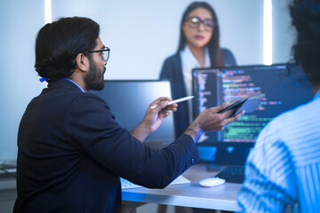 Diverse team of AI developers collaborating in a modern office. Indian male leading a discussion...