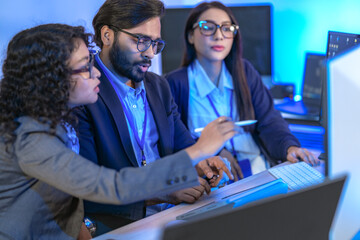 Diverse team of AI developers collaborating in a modern office. Indian male leading a discussion...