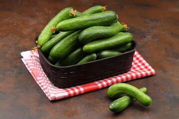 Fresh green cucumbers in a small wooden vegetable crate.