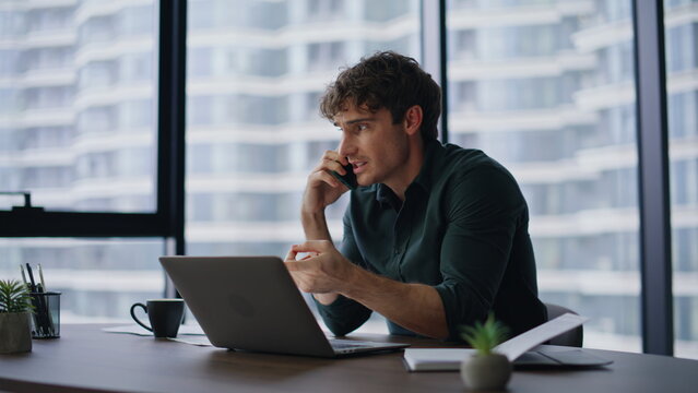 Worried executive talking cellphone discussing document mistake in modern office