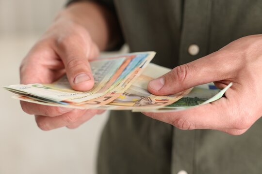 Man counting his money indoors, closeup view
