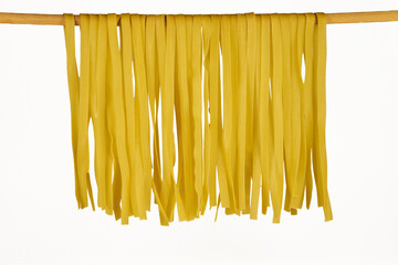Fresh egg fettuccine noodles, drying in close-up against a white background with copy space