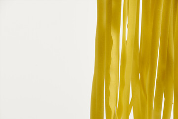 Fresh egg fettuccine noodles, drying in close-up against a white background with copy space