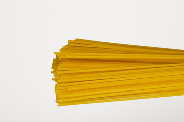 Raw spaghetti in a bundle tied with string on a white background with copy space, traditional...