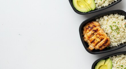 Grilled Chicken Meal Prep with Cauliflower Rice and Avocado Slices in Black Containers on White Background
