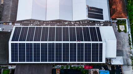 Aerial view of photovoltaic solar panels installed on the metal roof of a commercial building or...