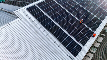 Solar power technician inspecting rooftop solar panels, performing maintenance and installation of...