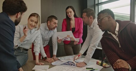 A diverse team of business professionals collaborates on a project, reviewing blueprints and discussing strategies in a modern office. - Powered by Adobe