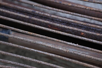 several old iron pipes covered with rust, laid out on a cement surface. The corrosion on the metal...