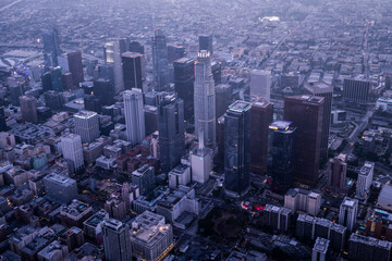 Aerial twilight view of downtown Los Angeles skyline with skyscrapers and modern office buildings rising above the urban sprawl in soft blue light