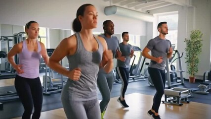 Diverse group of people running on treadmills in a bright modern gym engaging in cardio workout - Powered by Adobe