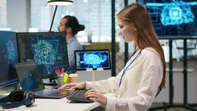 Junior dev in office relies on AI tech to run tasks across multiple devices, monitoring progress on screens. Young worker uses neural networks to develop artificial intelligence models, camera A