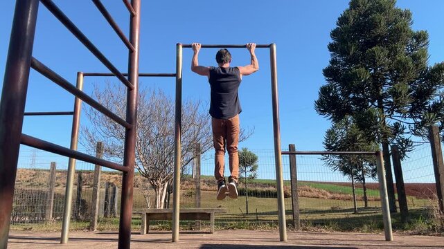 homem faz treino de calistenia exerc&iacute;cios em parque 
