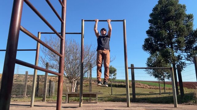 homem faz treino de calistenia exerc&iacute;cios em parque 