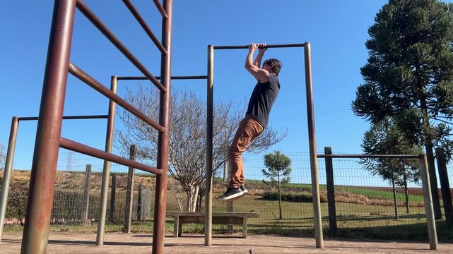 homem faz treino de calistenia exerc&iacute;cios em parque 