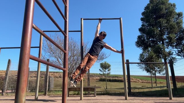 homem faz treino de calistenia exerc&iacute;cios em parque 