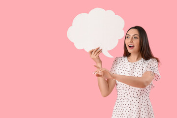 Young woman with blank speech bubble pointing at something on pink background