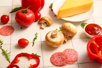Different ingredients for preparing pizza on white tile background