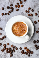 Cup of hot espresso and coffee beans on grey grunge background