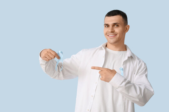 Handsome man with blue ribbons on color background. Prostate cancer concept