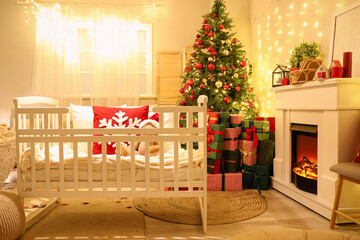 Interior of bedroom with baby crib, Christmas tree and glowing lights in evening