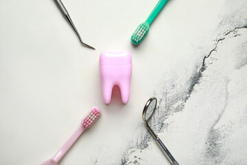 Tooth model, dental tools and toothbrushes on white marble background. World Dentist Day