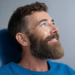 Obraz premium Middle aged man with beard and blue shirt looking up smiling close up profile