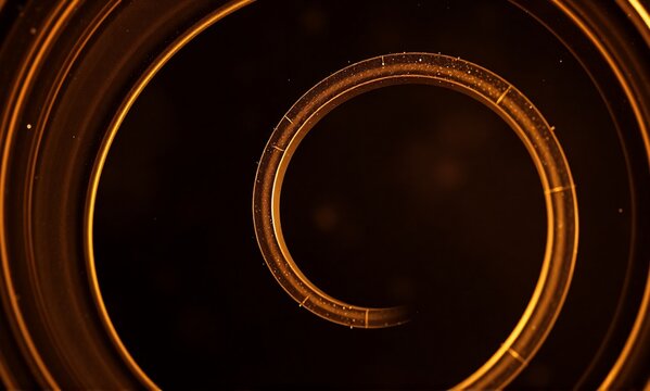 A glowing golden spiral descends into a dark, abstract void, creating a mesmerizing tunnel effect with subtle particles.