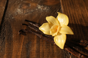 Beautiful vanilla flower and sticks on wooden background