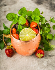 Refreshing Moscow mule cocktail with strawberries on the rustic background. Selective focus.