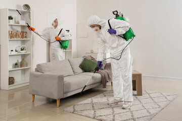 Male workers in hazmat suits disinfecting room