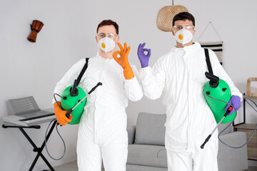 Male workers with disinfectant showing OK in room