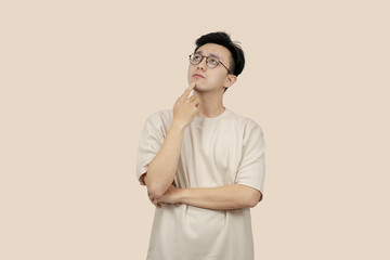 Thoughtful Young asian Man Contemplating Ideas While Standing Against a Neutral Background